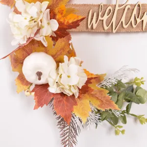 Autumn artificial maple leaf pumpkin wreath detail with welcome wooden sign for home door.