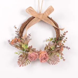 Detailed view of artificial pink rose wreath with rustic burlap bow and eucalyptus foliage.