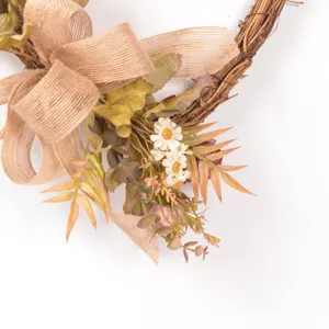 Close-up detail of vintage heart rattan wreath with burlap bow and artificial flower decor.