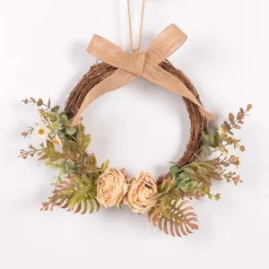 Detailed close-up of autumn vintage artificial flower wreath with rustic burlap bow and green leaves.