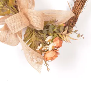 Close-up detail of rustic vine wreath featuring burlap bow, artificial roses and cute daisies.