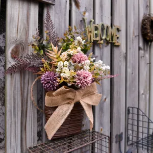 Close-up detail of artificial hanging flower basket with rustic burlap bow and wood wall.