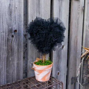 Close up of black tulle heart topiary plant in rustic terracotta pot for home decor detail.