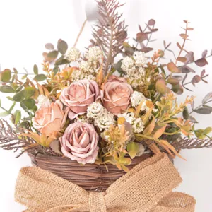 Close up of artificial flower wall hanging basket with vintage roses and rustic burlap bow decor.