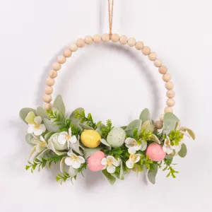 Easter wooden bead wreath hanging detail showing colorful eggs, green leaves and white flowers.