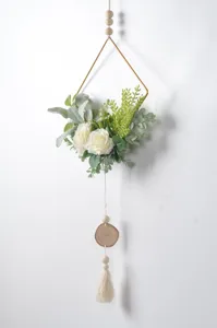Closeup of Nordic iron frame wall hanging with white artificial roses, wooden beads and tassel detail.