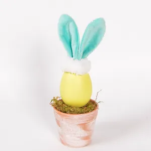 Easter bunny egg potted plant detail, cute plush rabbit ears with moss in terracotta pot.
