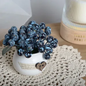 Detailed close-up of artificial blue berry potted plant, cute ceramic pot for home decor.