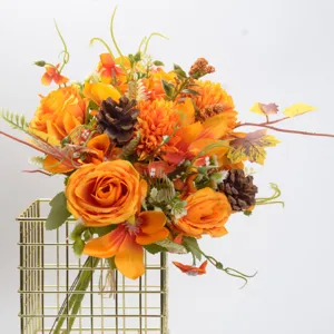Artificial autumn flower bouquet with roses and pinecones in gold holder for home decor.