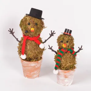 Close-up detail of handcrafted moss snowman figurine in terracotta pot with knit scarf.