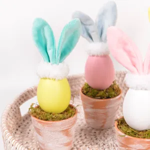 Close-up detail of cute Easter bunny ear egg potted ornament with moss and terracotta pot for decor.