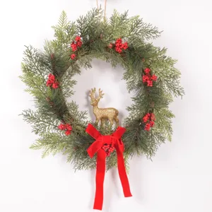 Christmas wreath detail showcasing artificial pine branches, red berries, and glitter deer.