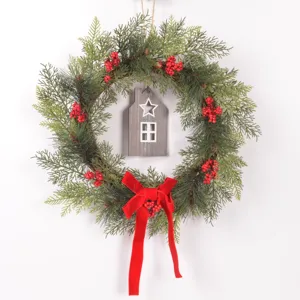 Christmas pine wreath with red berries, wooden house ornament and velvet bow for door decor.