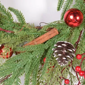 Christmas wreath detail shot with artificial pine needles, red baubles, cinnamon and pinecone
