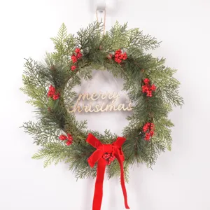 Christmas wreath detail featuring artificial pine branches, red berries and velvet bow.