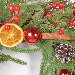 Close-up detail of Christmas wreath with pine needles, dried orange and berries for holiday decor.