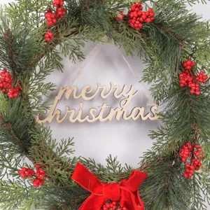 Christmas wreath with pine branches, red berries, velvet bow and wooden merry christmas sign.