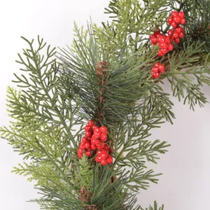 Close up of artificial Christmas pine wreath branches with red berries for holiday decor