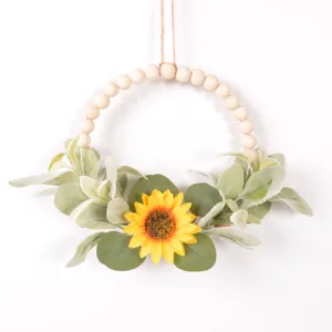 Close-up detail of artificial sunflower and wooden bead wreath for seasonal wall hanging decor.