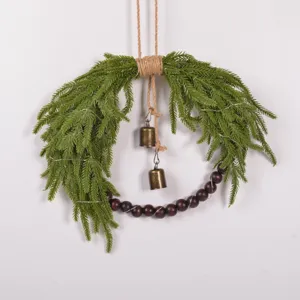 Detail view of the Christmas pine wreath showing wooden beads and rustic brass hanging bells.