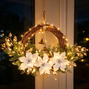 Bella ghirlanda decorativa di Natale con luci calde, poinsettia bianche e campanelle.