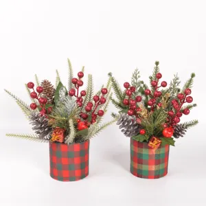 Christmas table decoration detail featuring pine branches, glitter berries and plaid pots.