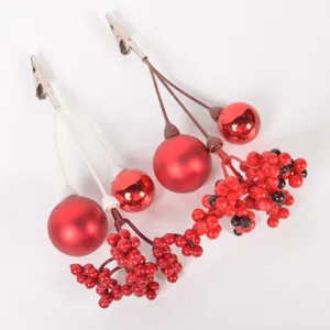 Close-up detail of Christmas decorative clips with red berries and shiny baubles for DIY crafts.