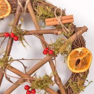 Closeup of rustic twig wreath with dried orange slices, moss, cinnamon and red berries.
