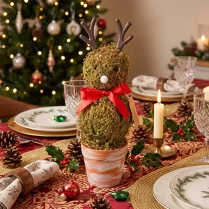 Close-up of a festive moss reindeer potted decoration on a decorated Christmas table.