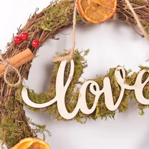 Christmas forest style wooden letter rattan wreath detail view with dry orange and moss.