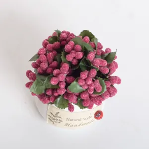 Close-up of mini artificial berry potted plant, frosted pink berries and green leaves details.