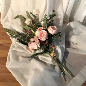 Details of vintage artificial flower bouquet with pink roses and leaves for home decor.