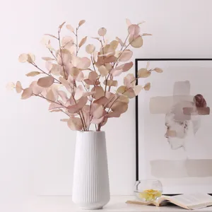 Detailed view of artificial eucalyptus leaves in a white ceramic vase for home desktop decor.