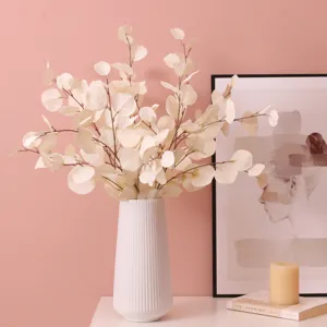 Detailed view of artificial eucalyptus leaves in a white ceramic vase, perfect for home decor.