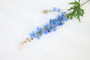 Detailed view of artificial delphinium flower branch, showing realistic blue blooms and green leaves.