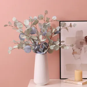 Artificial eucalyptus leaves in a white ceramic vase, perfect for home decor and tabletop display.