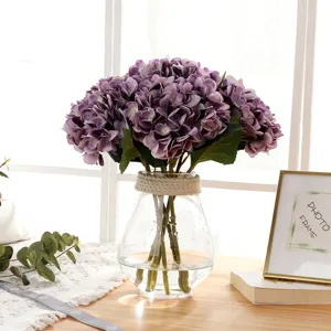 Close-up display of artificial purple hydrangea bouquet arranged in a clear glass vase.