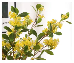 Close-up detail of artificial yellow osmanthus flower branch with green leaves for nice indoor decor.
