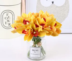 Detail view of artificial orchid flower bouquet in glass vase, elegant yellow home decor ornament.