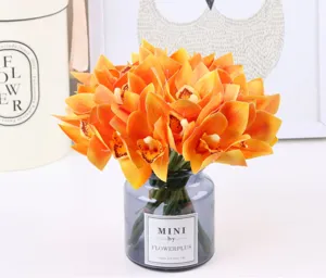 Detailed view of artificial orange cymbidium orchid bouquet in grey glass vase for home decor.