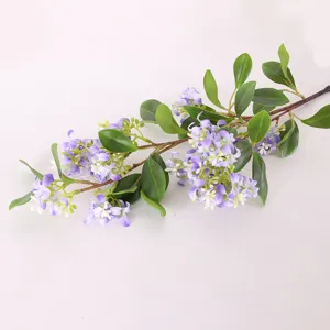 Detailed close-up of artificial purple flower branch with green leaves for home decor.