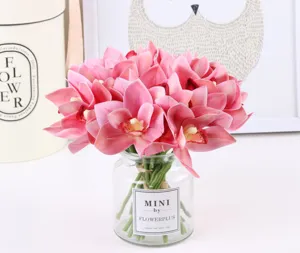Close-up detail of artificial pink orchid flower bouquet in clear glass jar vase for home decor