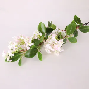 Detailed shot of artificial flower branch with pink blossoms and green leaves for home decor.