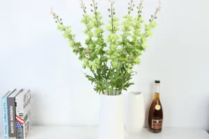 Artificial green delphinium flowers in white vase for home decor and wedding party styling.