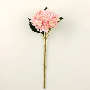 Primo piano di uno stelo di ortensia artificiale rosa con foglie verdi per decorazioni.