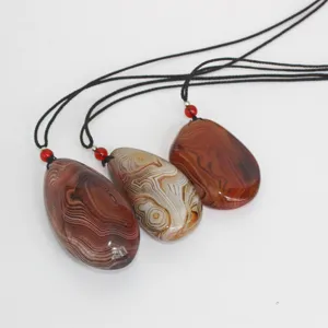 Detail of natural polished banded agate stone pendant necklace showing unique texture patterns.