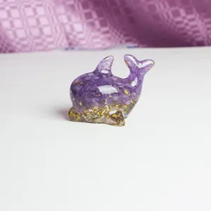Détail de figurine de dauphin en résine de cristal faite main, gravier violet et feuille d'or.