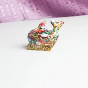 Détail d'artisanat dauphin en résine avec des éclats de cristal colorés et des paillettes.