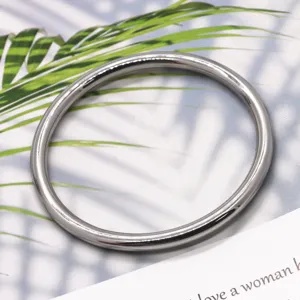 Close-up detail of smooth metal bangle bracelet, minimalist silver tone jewelry design.