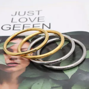 Close-up of four minimalist metal bangles in gold and silver with smooth and matte finishes.